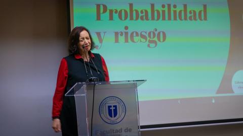 Una mujer presenta un tema sobre probabilidad y riesgo en una sala de clases.