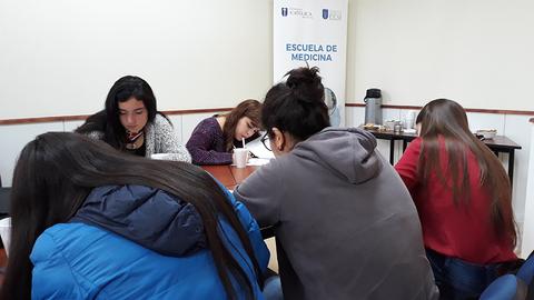 Un grupo de estudiantes de medicina está concentrado en una actividad académica en un aula.