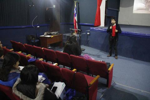 Un presentador habla frente a un grupo de personas en un auditorio.