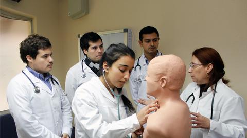Un grupo de estudiantes de medicina está aprendiendo a practicar un examen médico en un maniquí en un aula.