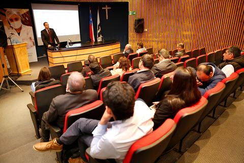 Un grupo de personas asiste a una presentación en un auditorio con un orador en el frente.