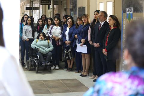 Un grupo diverso de personas se reúne en un pasillo, con algunas en posiciones de liderazgo y otras escuchando atentamente.