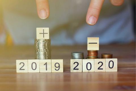 La imagen muestra dos montones de monedas con bloques que representan los años 2019 y 2020, simbolizando un cambio de situación financiera.