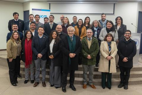 Un grupo de profesionales posando en un evento formal en un recinto cerrado.
