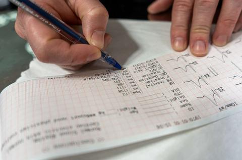 Una persona está escribiendo en una hoja con gráficos y datos médicos.