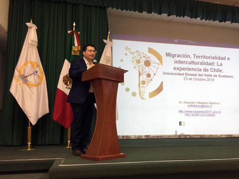 Un conferencista presenta sobre migración y multiculturalidad en un evento académico.