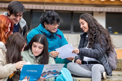Un grupo de jóvenes en un ambiente relajado compartiendo documentos y riendo juntos.