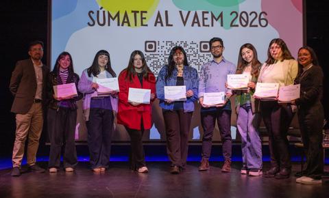 Ocho estudiantes celebran su graduación en un evento con diplomas en mano.