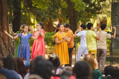 Un grupo de niños se presenta en un escenario al aire libre, mostrando su talento en una actuación.