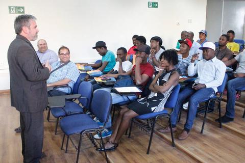 Un profesor está dando una clase frente a un grupo de estudiantes en un aula.