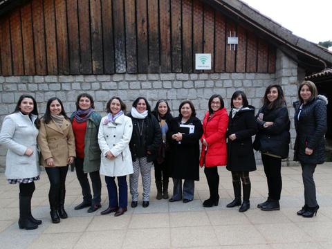 Un grupo de mujeres posando frente a un edificio de madera en un ambiente al aire libre.