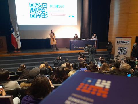 Un evento en un auditorio en Chile donde se presenta información sobre las votaciones nacionales.