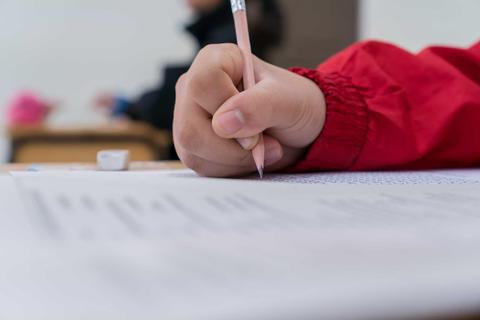 Un cabro chico escribiendo en su cuaderno en clase.