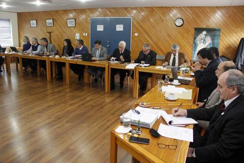 Reunión de un grupo de personas sentadas alrededor de una mesa en un ambiente formal.