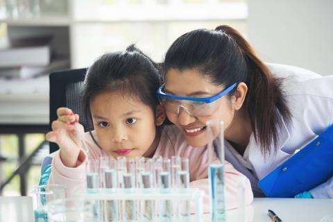 Una madre y su hija disfrutan de una actividad científica juntas en un laboratorio.