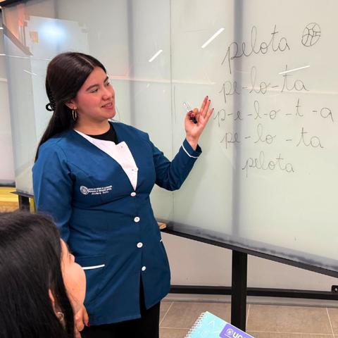 Una docente enseña a sus alumnos sobre la palabra 'pelota' en una pizarra.