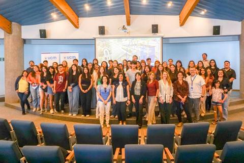 Un grupo grande de personas posando en un auditorio para una fotografía grupal.
