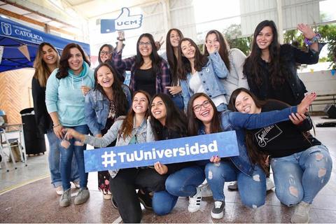 Grupo de estudiantes posando felices con una pancarta en un evento universitario.