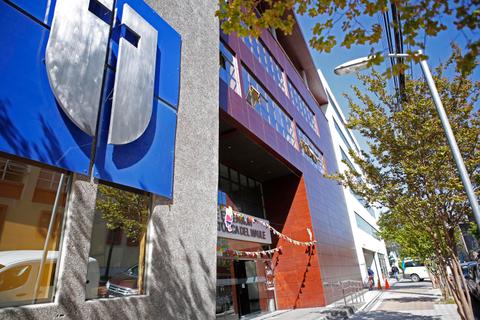 Edificio moderno con un gran logotipo en la fachada y árboles al lado.