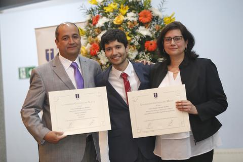 Tres personas posan sonrientes con diplomas en un evento de graduación.