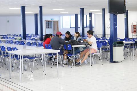Un grupo de seis personas se encuentra sentada en una mesa en un comedor amplio.