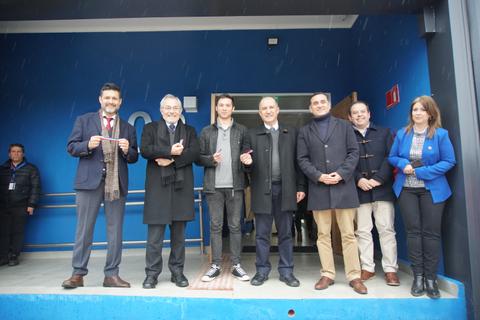 Un grupo de personas posando frente a un edificio con paredes de color azul.