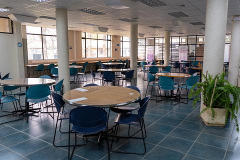 Una sala amplio con mesas y sillas vacías en un ambiente iluminado.