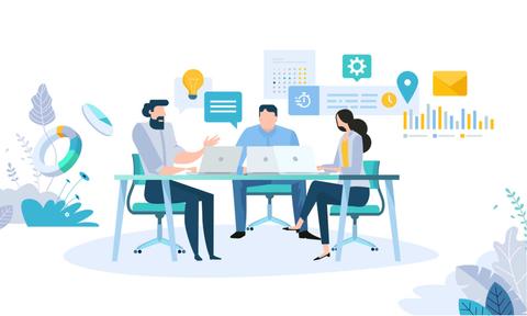 Tres personas discuten en una mesa con equipos de trabajo y elementos gráficos alrededor.