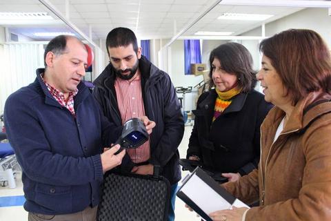 Un grupo de personas observa un dispositivo tecnológico en un entorno de trabajo.