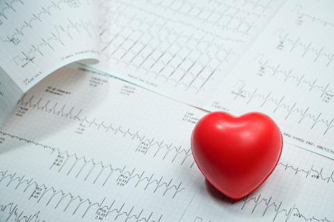 Una figura en forma de corazón rojo sobre un fondo de gráficos de electrocardiogramas.