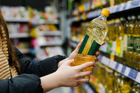 Una persona sostiene una botella de aceite en un supermercado.