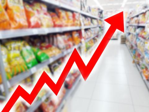Una gráfica ascendente sobre un fondo de pasillo de supermercado lleno de productos.
