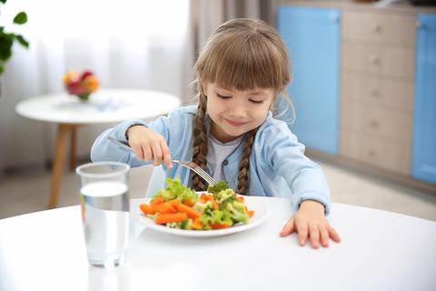 Una niña está disfrutando de una comida saludable en una mesa clara.