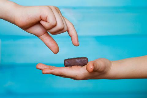 Dos manos de niños interactuando con un dulce sobre una palma.