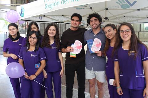 Un grupo de jóvenes sonríe y sostiene folletos en un evento comunitario.