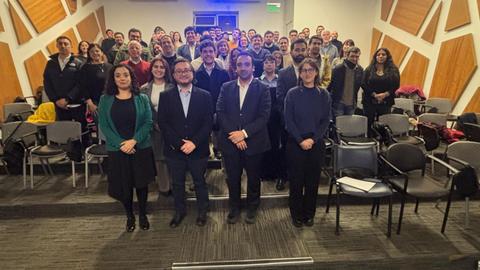 Una foto de un grupo grande de personas en un auditorio, todos posando juntos con sonrisas.