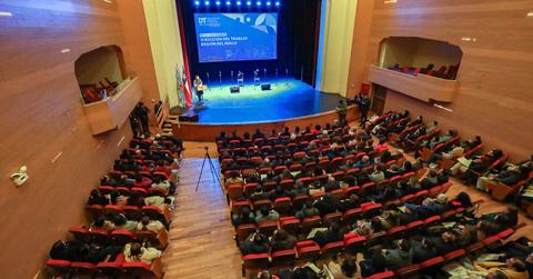Un auditorio lleno de público durante un evento con un escenario iluminado.