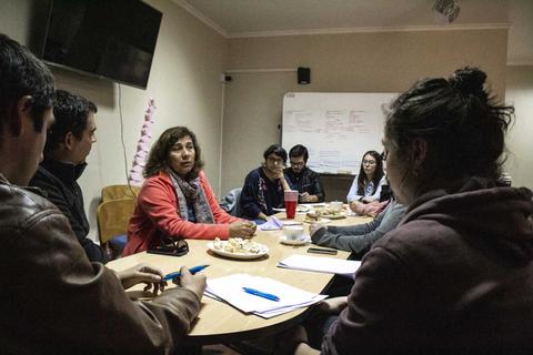 Una reunión de trabajo con varias personas sentadas alrededor de una mesa, en un ambiente colaborativo.
