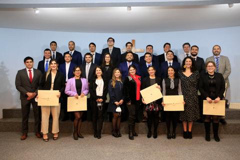 Un grupo de personas posando juntas en un evento formal con diplomas en las manos.