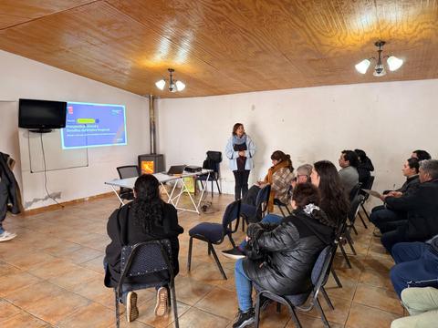 En una sala de reunión, un grupo de personas asiste a una presentación frente a una pantalla.