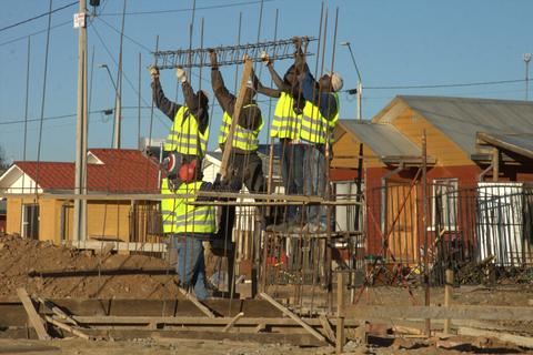 Un grupo de trabajadores en un sitio de construcción levantando una estructura metálica.
