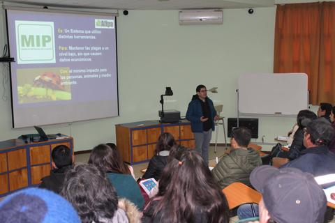 Una presentación en un aula sobre un sistema de control de plagas con un ponente frente a una pantalla.