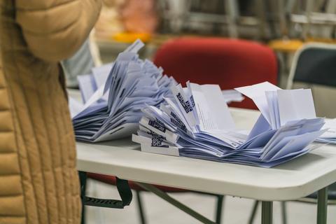 Una mesa con papeletas de votación apiladas en un entorno de elección.