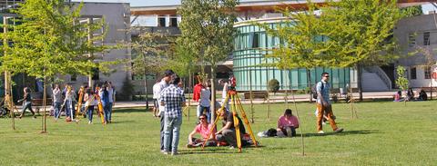 Un grupo de personas se reúne en un parque con edificios modernos de fondo.