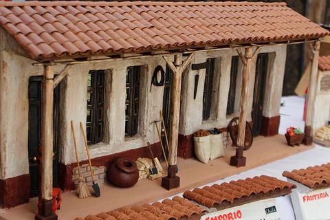 La imagen muestra una maqueta de una tienda con un techo de tejas y elementos decorativos en su exterior.