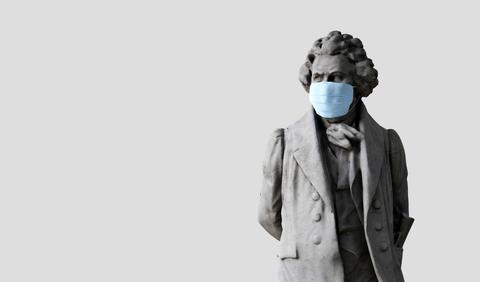 Una escultura que muestra a un hombre con una mascarilla azul en un fondo gris.