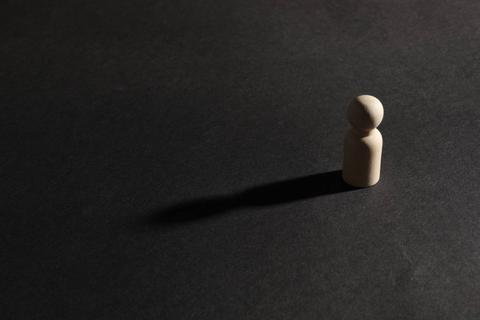 Una figura de madera se encuentra sola sobre un fondo oscuro.