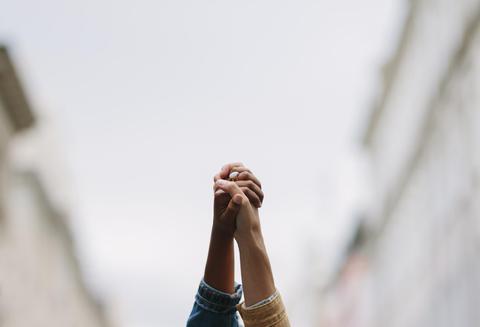 Dos manos entrelazadas se levantan hacia el cielo.
