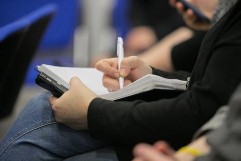 Una persona está tomando notas en un cuaderno mientras sostiene un bolígrafo.