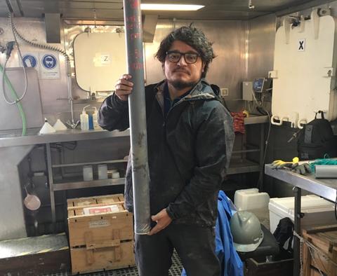 Una persona sostiene un tubo metálico en un entorno de trabajo.